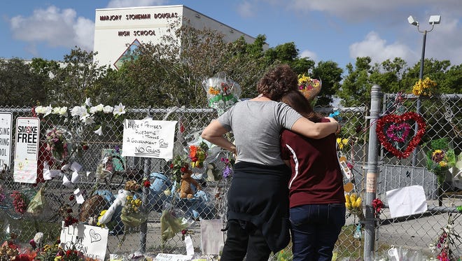 Margarita Lasalle, right, the budget keeper, and Joellen Berman, Guidance Data Specialist, look on at the memorial in front of Marjory Stoneman Douglas High School as teachers and staff are allowed to return to the school for the first time since the mass shooting on campus on February 23, 2018 in Parkland, Florida.