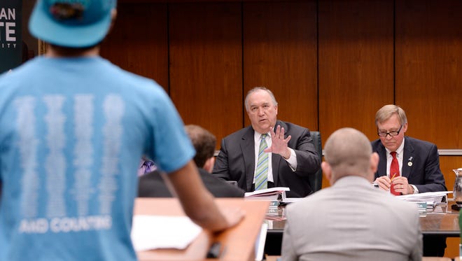 John Engler, interim president of Michigan State University, tells student Dan Martel, 21, president of the MSU College Democrats, that his five-minute time limit is up during the board of trustees meeting Friday.
