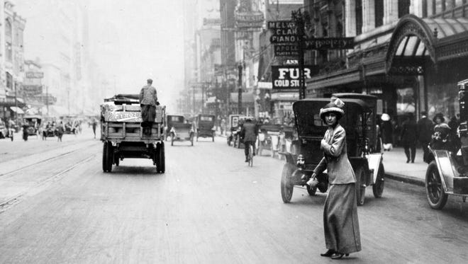 A woman attempts to cross Woodward Avenue in 1911.  In the early years of  motoring, three-fourths of auto accident victims were pedestrians, and one-third of the pedestrian victims were children.