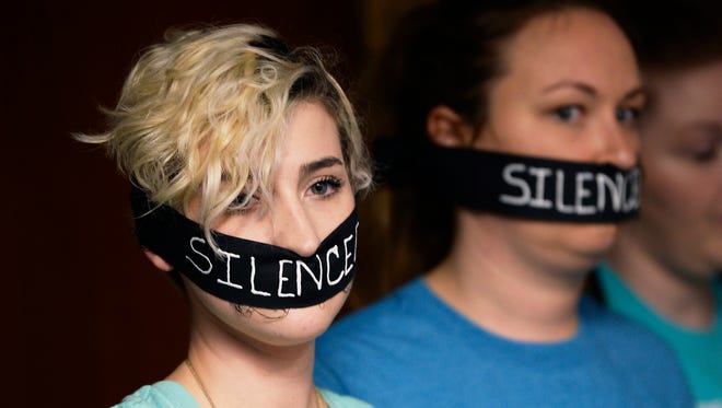 From left, Amanda Thomashow, 28, and Alex Neil-Sevier, 29, wear silence gags while listening to the meeting.