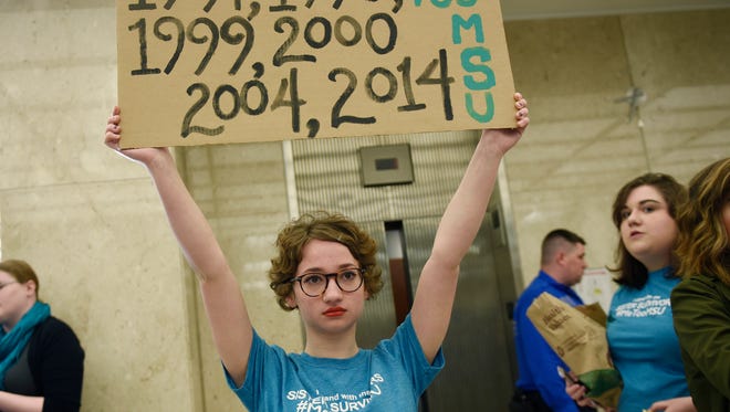 Morgan McCaul, 18, a survivor of Larry Nassar abuse, holds a sign showing the years that the disgraced sports doctor's sexual activity was reported to MSU officials. She and others were protesting in the Hannah Administration Building on MSU's campus in East Lansing.