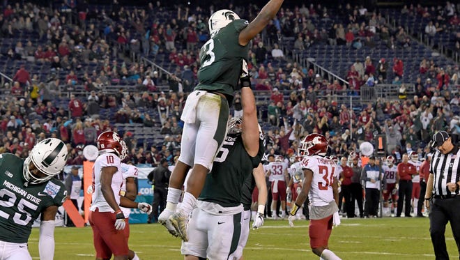 LJ Scott and teammates celebrate a fourth-quarter touchdown in Michigan State's 42-17 victory in the Holiday Bowl Thursday.