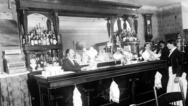 A waiter and bartenders are seen in the Garibaldi Saloon at 20 Monroe, circa 1898.