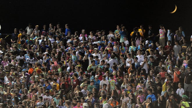 The moon rises over the Rochester Adams student section during a high school football game against West Bloomfield.