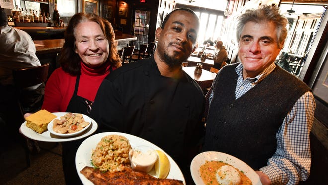 Howe's Bayou chef Rafael Branhan, center, holding a plate of blackened catfish with dirty rice, with partners Patti Barker, holding a plate of butter beans and corn bread and Michael Hennes holding a bowl of crawfish etouffee at the Ferndale, Michigan restaurant on Feb. 8, 2018.