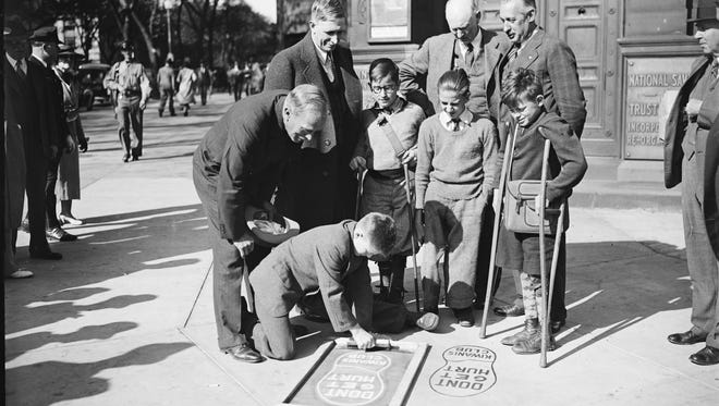 Students at a school for the disabled paint giant footprints at dangerous intersections as warnings to pedestrians in Washington, D.C. in 1935.