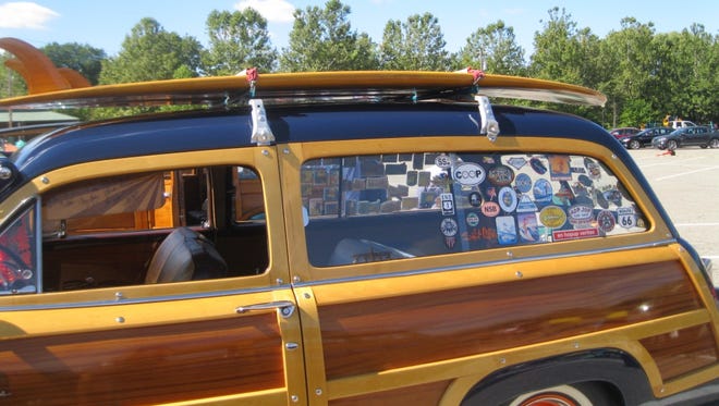 Travel stickers adorn the rear window of the '51 Ford Country Squire, which sports a surfboard on top.