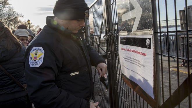 A United States Park Police officer post a sign informing of the Statue of Liberty and Ellis Island closing at an entrance to the ferry, Saturday, Jan. 20, 2018, in New York.