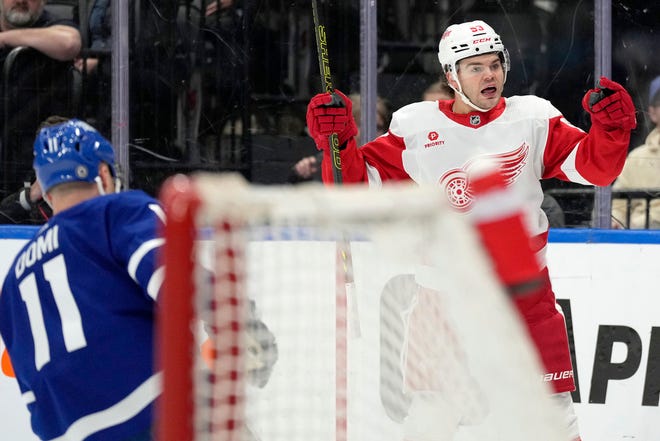 Red Wings right wing Alex DeBrincat (93) celebrates his goal as Maple Leafs center Max Domi (11) looks on during the first period.