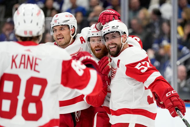 Red Wings left wing David Perron (57) celebrates his goal against the Maple Leafs with Patrick Kane (88), Ben Chiarot (8) and J.T. Compher (37) during the first period.