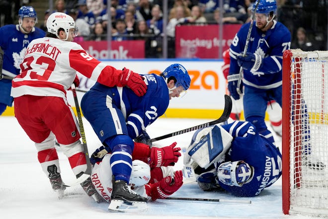 Maple Leafs defenseman Jake McCabe (22) takes down Red Wings left wing Lucas Raymond (23) after he collided with Leafs goalie Ilya Samsonov (35) during the first period.