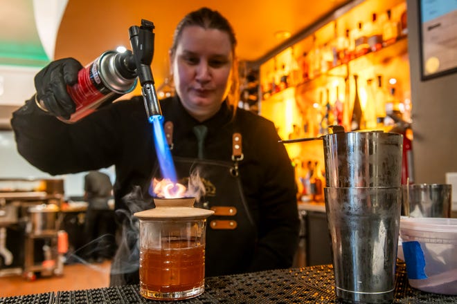 MeganPaige Hausner, bartender at Table No. 2, an upscale restaurant in Detroit's Greektown, right, makes a cocktail called "Smoke Show" at the restaurant on Thursday, April 18, 2024.