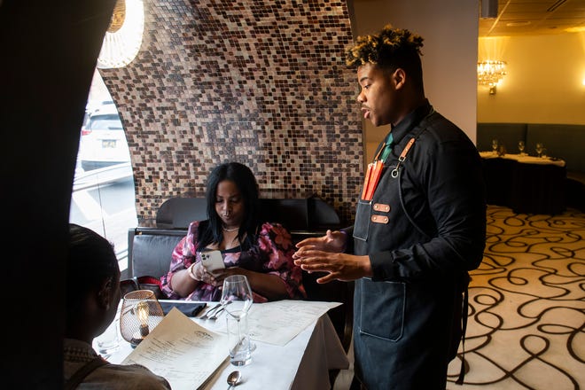 Amir Mitchell, a server at Table No. 2, an upscale restaurant in Detroit's Greektown, right, greets a table of diners on Thursday, April 18, 2024.