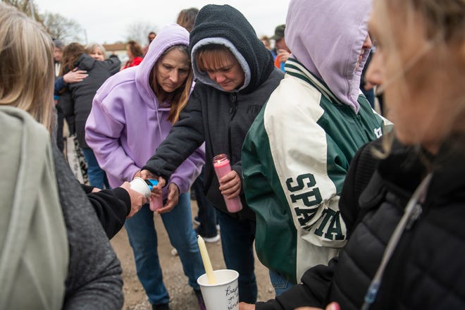 Community members Danette Kench, left, and Tonya Melfi, right, attempt to light their candles during a vigil in honor of Alanah Phillips, 8, and Zayn Phillips, 4, on Friday, April 26, 2024, at the Swan Boat Club in Newport, Michigan.