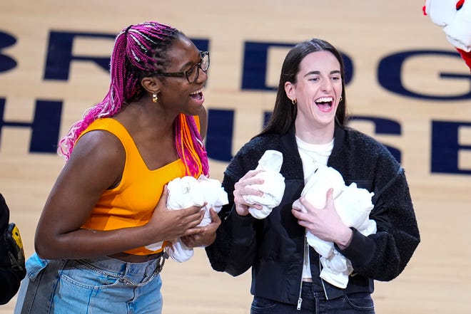 Indiana Fever players Aliyah Boston, left, and Caitlin Clark throw tee-shirts to fans during a time out during the first half between the Indiana Pacers and the Milwaukee Bucks in Game 2 of the NBA first-round playoff series on Friday in Indianapolis.