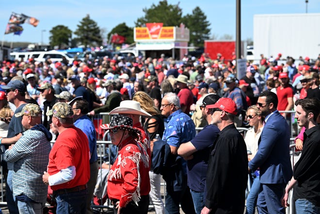 People stand in line to go through security before the Donald Trump rally at Avflight Saginaw at MBS International Airport in Freeland, Mich. on May 1, 2024.