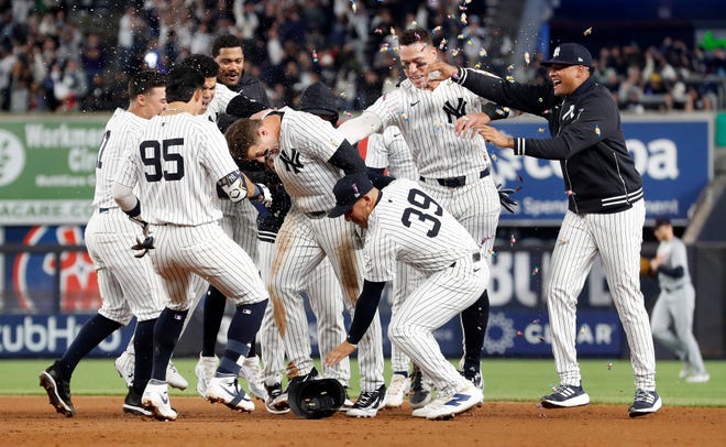Anthony Rizzo #48 of the New York Yankees is mobbed by his teammates after his ninth inning game winning base hit.