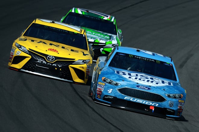 Kevin Harvick, right, leads a pack of cars during the NASCAR Cup Series Consumers Energy 400 at Michigan International Speedway.