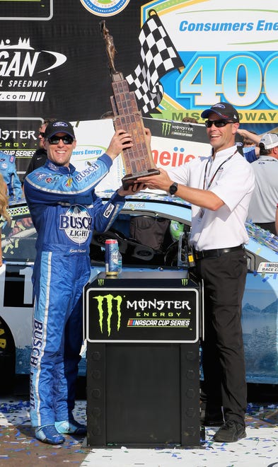 Kevin Harvick celebrates with the trophy in Victory Lane after winning the NASCAR Cup Series Consumers Energy 400 at Michigan International Speedway.