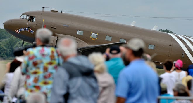 A Douglas C-47 Skytrain military transport aircraft taxis by the crowd.