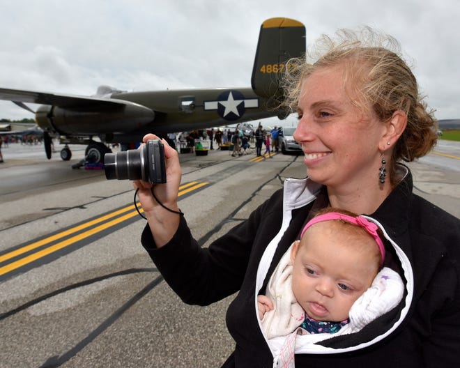 Cheryl LaRoy takes pictures as her three-month-old daughter, Anna LaRoy, both of Kalamazoo, wakes up from a nap during the Thunder Over Michigan Air Show at Willow Run Airport in Ypsilanti on August 25, 2018. In the background is a 1944 North American B-25 nicknamed, "Georgie's Gal" from the Liberty Aviation Museum in Port Clinton, Ohio.
