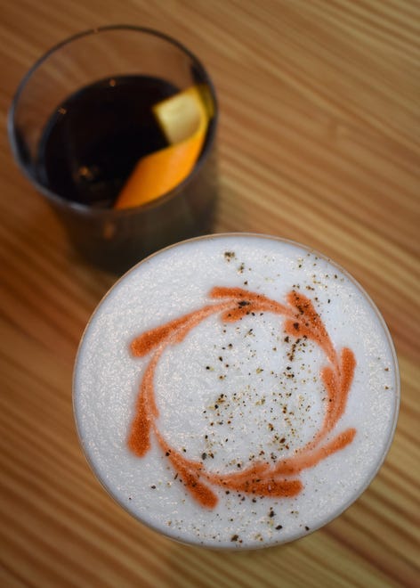 A new cocktail mixes mulled wine syrup with bourbon and cream de cassis, top; it is topped with an orange peel. The " Pepper + Smoke " cocktail is Famous Grouse, Kilchoman Sanaig, black pepper-lavender honey and egg white.