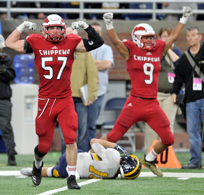 Chippewa Valley defensive lineman Michael Garwood (57) flexes after stopping Clarkston's Josh Luther from scoring a two-point conversion  as teammate Courtney McGarity (9) also celebrates.