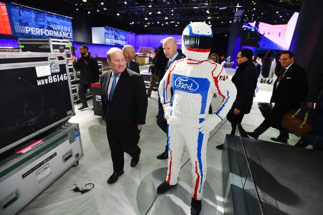 Detroit Mayor Mike Duggan walks past a Ford race car driver made out of Legos at the Ford display during a behind-the-scenes tour as construction continues on the North American International Auto Show at Cobo Center in Detroit on January 7, 2019.