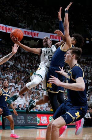 Michigan State's Cassius Winston goes to the basket against Michigan's Jordan Poole, center, and Colin Castleton, right, during the second half Saturday.