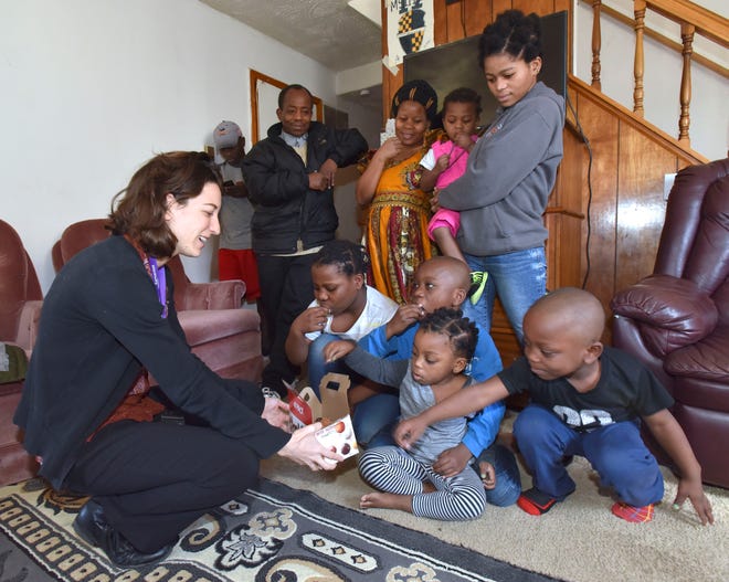 Samaritas' Christina Field, left, supervisor for employment and post settlement for New Americans, offers the children donuts. The Amani family lives in Warren now after spending 20 years in a refugee camp. Despite the few refugees resettling in Michigan, Congolese from the Dem. Rep. of Congo have been resettling in large numbers.