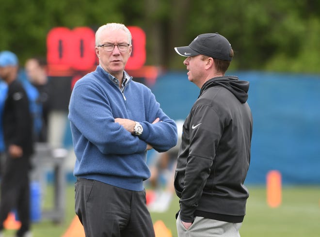 Lions president Rod Wood and general manager Bob Quinn chat on the field during practice.