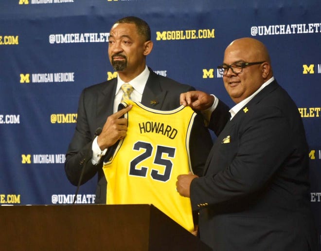 New Michigan head coach Juwan Howard (left) holds his old jersey with athletic director Warde Manuel on Thursday, May 30, 2019, at Crisler Center in Ann Arbor.