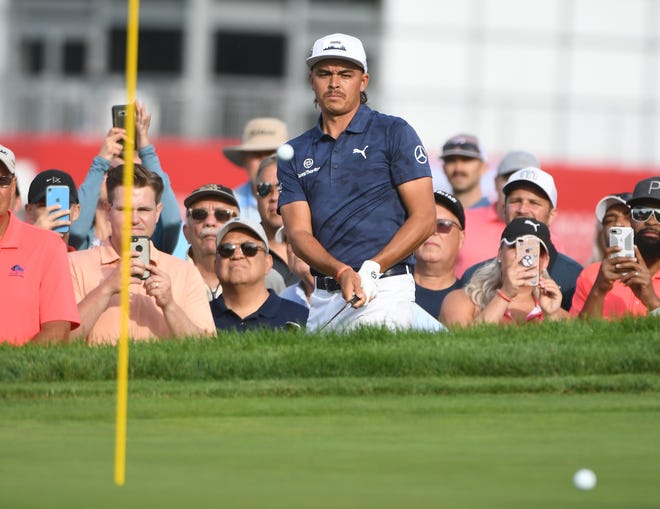 Rickie Fowler hits out of the rough along the 13th green.