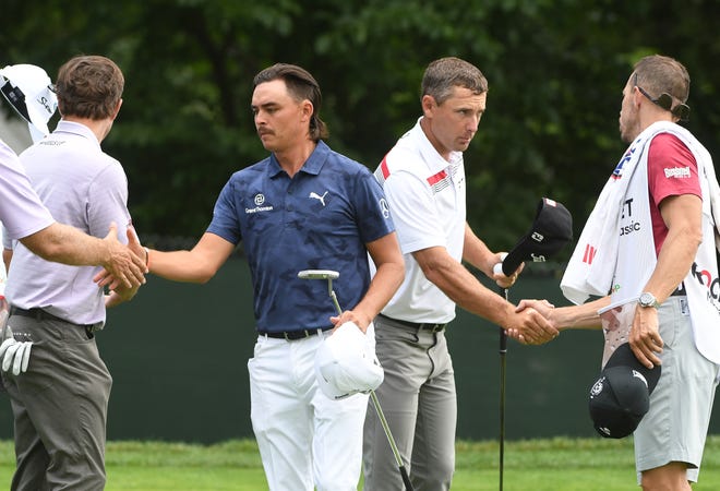 Rickie Fowler and Charles Howell III shake hands with players and caddies at the end of the first round.