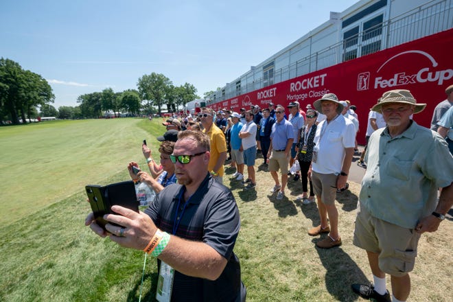 Fans try to get pictures of the golfers on the 10th hole.