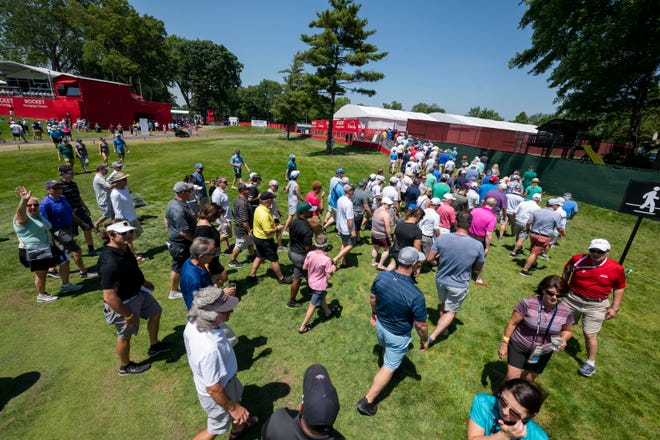 Fans cross over the course on hole 10 during the Rocket Mortgage Classic golf tournament.