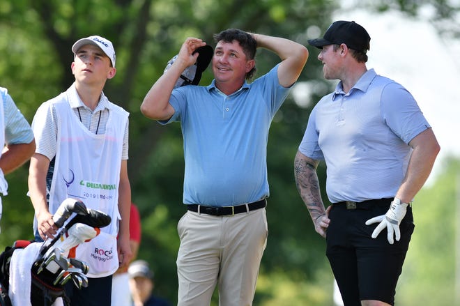 PGA golfer Jason Dufner talks with Red Wings goalie Jimmy Howard, right, while others tee off on hole No. 15.