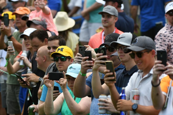 Fans take photos of their favorite golfers along the ninth fairway.