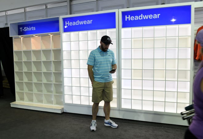 Surrounded by empty merchandise shelves, Nick Banaszak, 36, of Farmington, waits for a friend trying on a shirt at the PGA Tour Fan Shop.