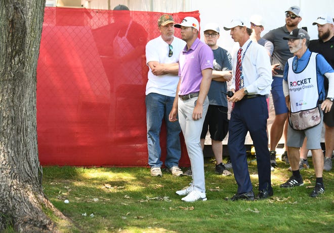 Sam Burns, in purple, listens to the PGA official, right, on the 10th fairway. Burns was not allowed to drop a ball on this spot where his ball landed behind a tree.