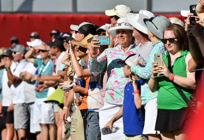 Fans take photos or video on the 18th hole at the Rocket Mortgage Classic.
