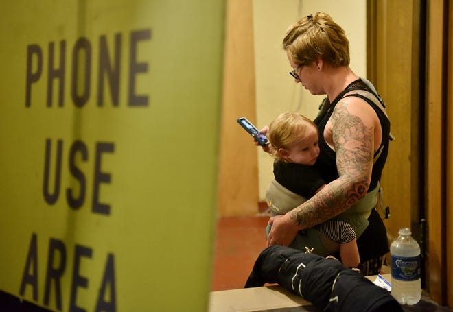 With perhaps the youngest attendee at the show, her 16-month-old daughter, Sabine Brown, Holly Brown, 36, of Mason checks her phone in the phone use area.