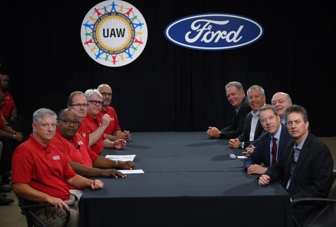 The UAW was represented by, front to back, Steve Zimmerla, Vice President Rory Gamble, President Gary Jones, President of UAW Local 600 Bernie Ricke and Tim Kenny.  Ford management was  represented by, back to front, Vice President Gary Johnson, Automotive President Joe Hinrichs, President and CEO Jim Hackett,  Executive Chairman William Clay Ford Jr. and Vice President Bill Dirksen.