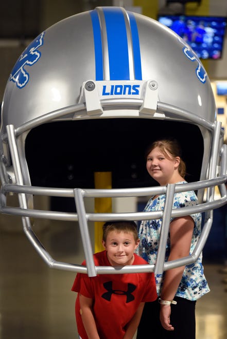 Nolan Nykse, 9, and Nicole Nykse, 11, of Monroe, pose for for a photo while standing inside a giant Lions replica helmet.