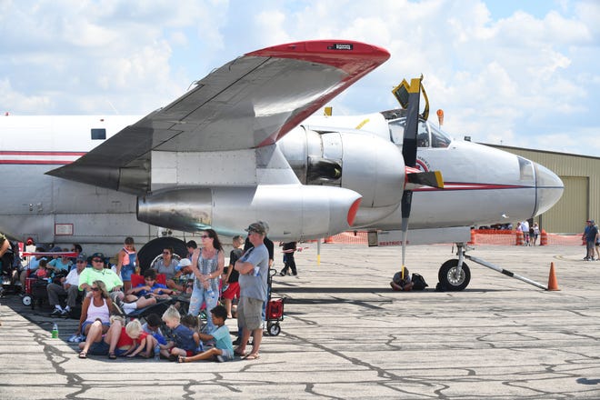 Visitors to the Thunder Over Michigan Air Show take shelter under the wing of a P2 Neptune, made by Lockheed.