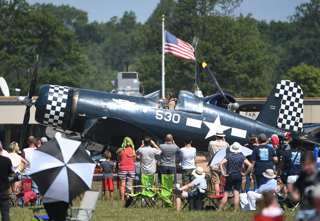 A Vought F4U Corsair taxis to the runway past an excited crowd of on-lookers.