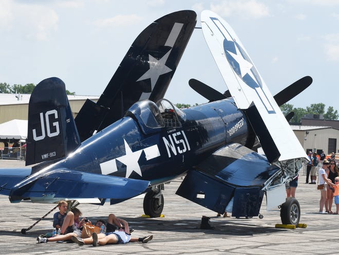 The Freundo family from Clarkston take a break under the tail section of a Vought F4U Corsair with its wings in a folded position.