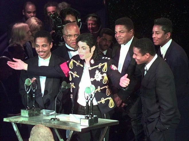 Michael Jackson, center, joins Motown Records mogul Berry Gordy, second from left, and Jackson's brothers, from left, Marlon, Tito, Jackie (front) and Jermaine, as the Jackson 5 are in inducted into the Rock and Roll Hall of Fame on May 6, 1997, in Cleveland.