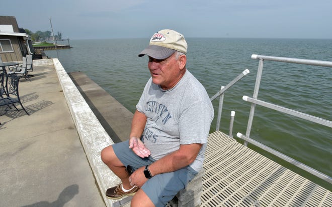 Killarney Beach resident Dan Latal talks about the rising water level of Saginaw Bay as he sits on the seawall behind his house. Latal says there were 100 yards of beach here when he moved in 19 years ago.