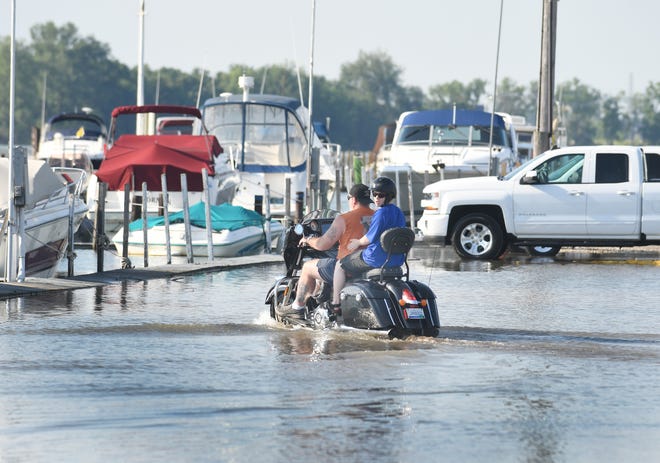 A motorcycle traverses high water on a usually dry parking lot at the Humbug Marina in Gibraltar on July 1, 2019.